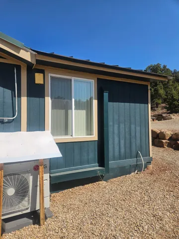 Exterior featuring vertical panel siding, light-colored trim, and a horizontal sliding window