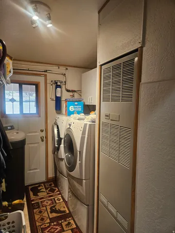 Dedicated utility room featuring a front-loading washer and dryer, integrated water filtration system, and built-in white cabinetry