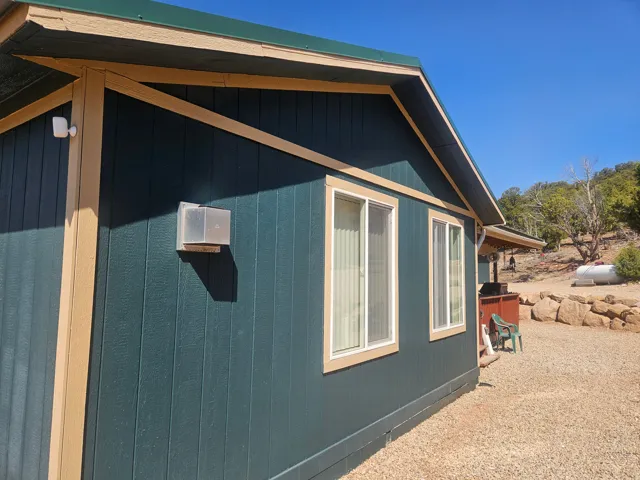 Deep teal vertical siding with tan trim and a dark green metal roof