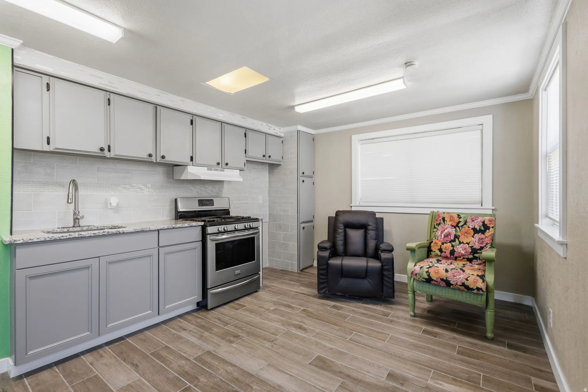 Contemporary kitchen featuring light gray cabinetry, stainless steel range, and a single basin sink with a high-arc faucet