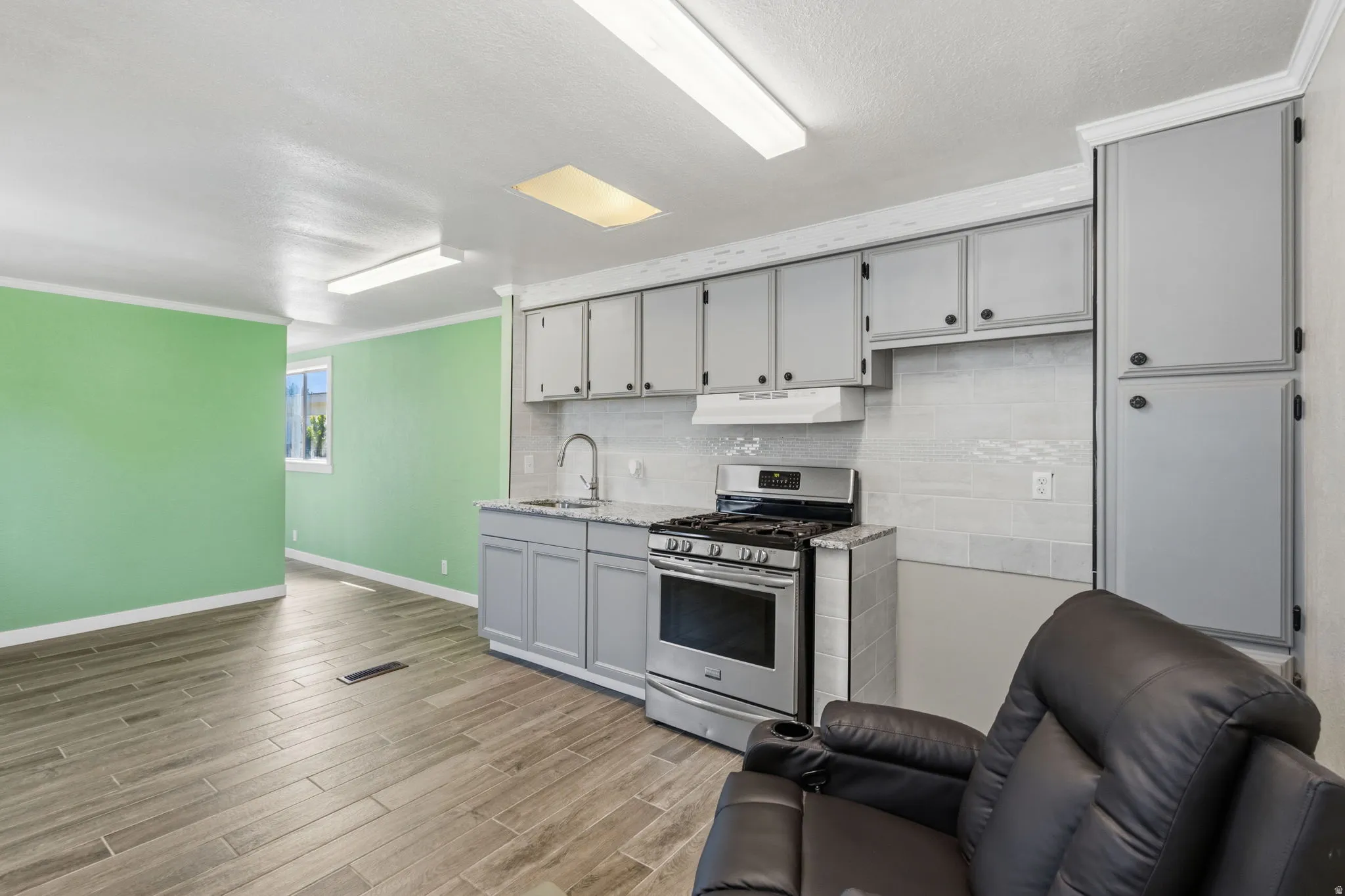 Kitchen area featuring light gray cabinetry, stainless steel range, and a subway tile backsplash