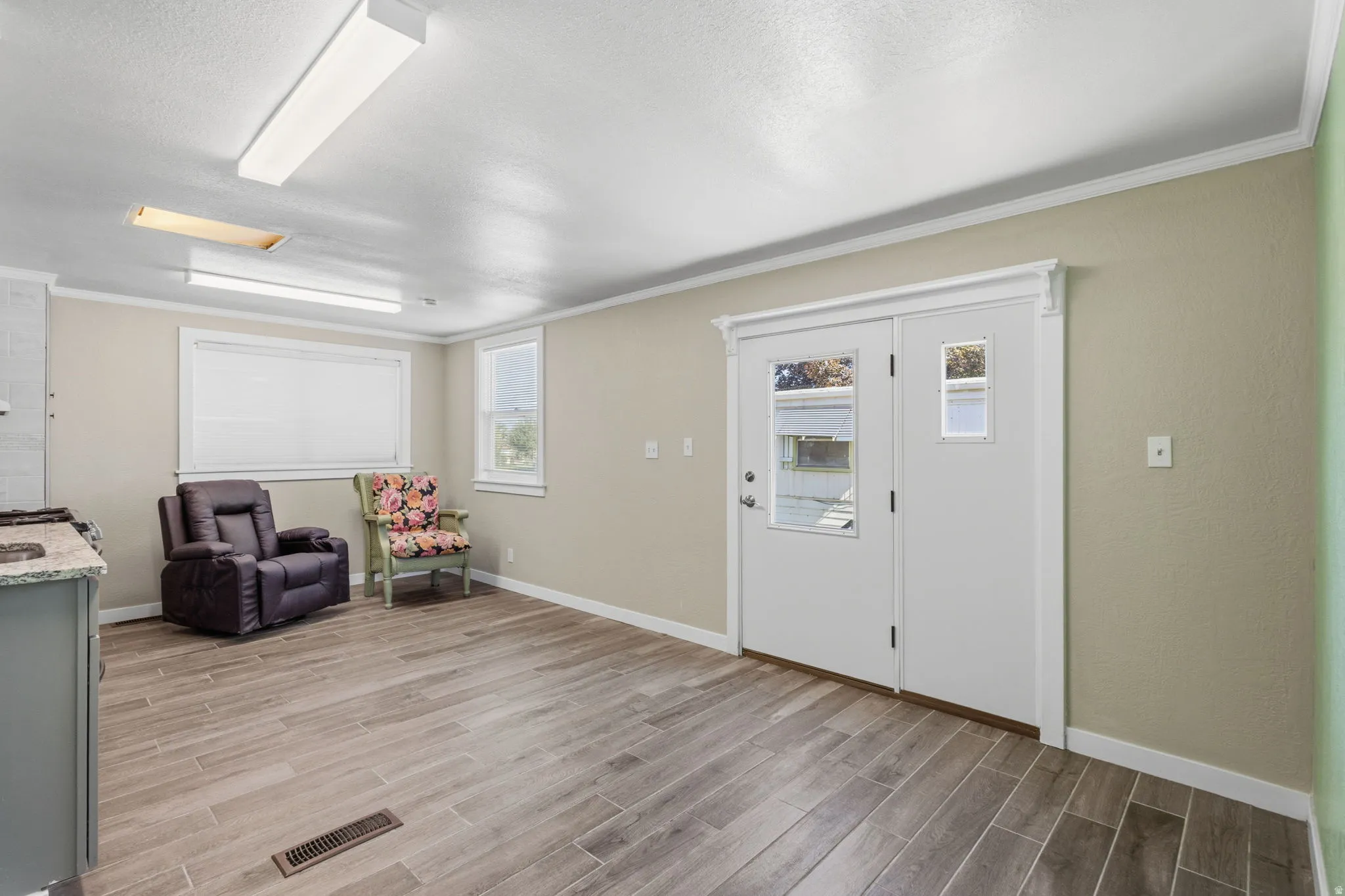 Spacious room featuring wood-finish tile flooring, neutral wall tones, and white trim