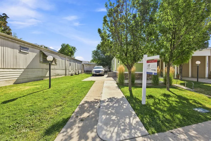 Concrete walkway with a grassy area and mature trees
