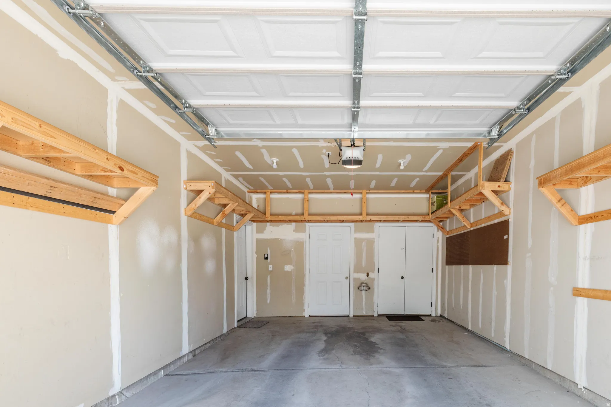 Spacious garage featuring a paneled overhead door, built-in wooden shelving, and a concrete floor