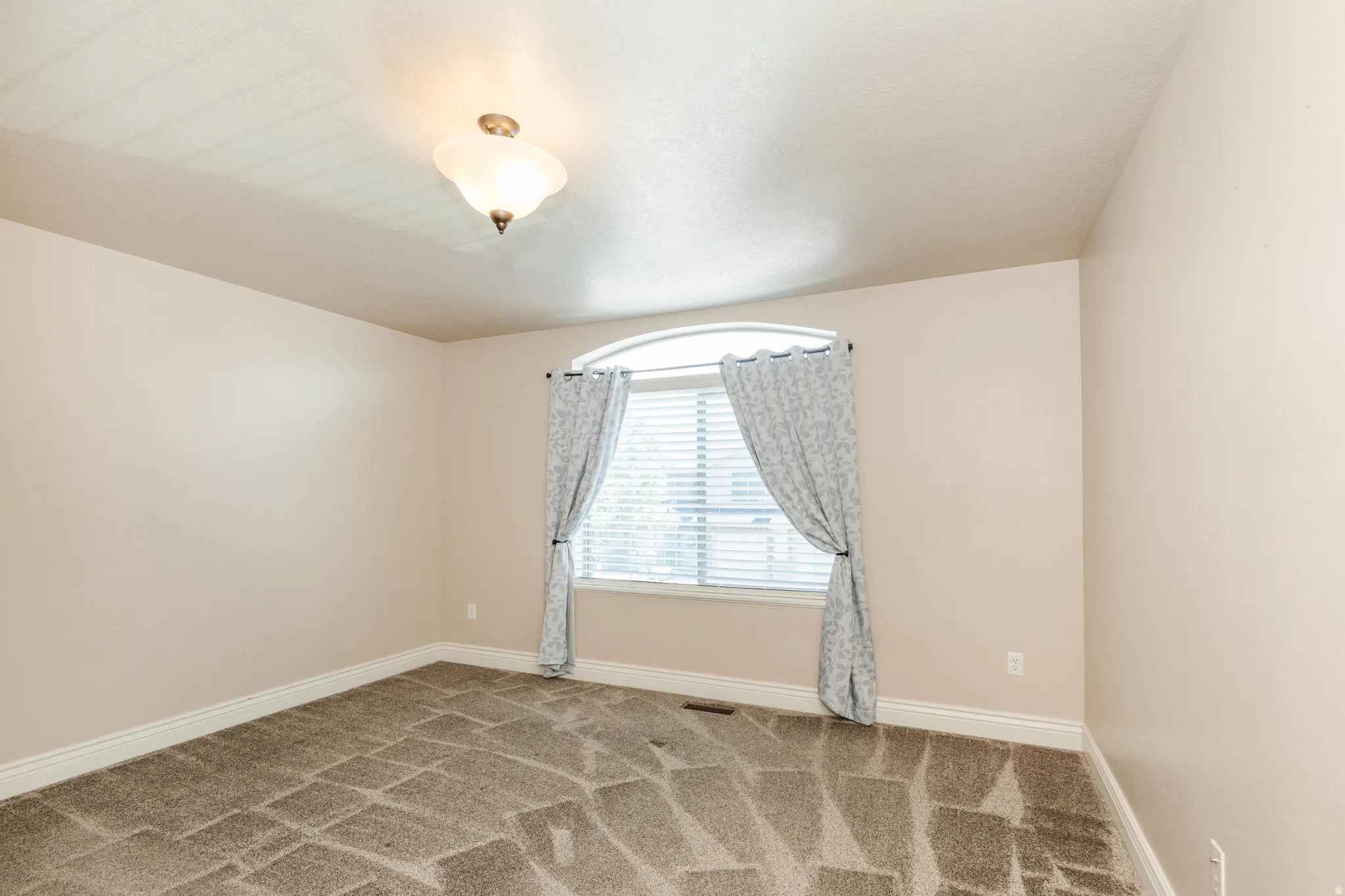 Room featuring patterned carpeting, neutral wall paint, and white baseboards
