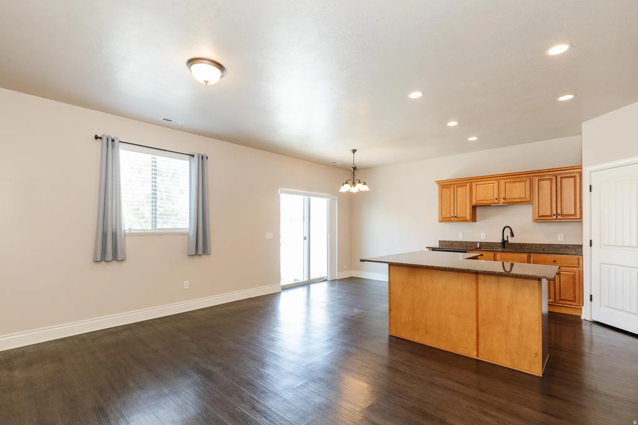 Open concept living space featuring wood-finish flooring, recessed lighting, and a modern kitchen island with an extended countertop