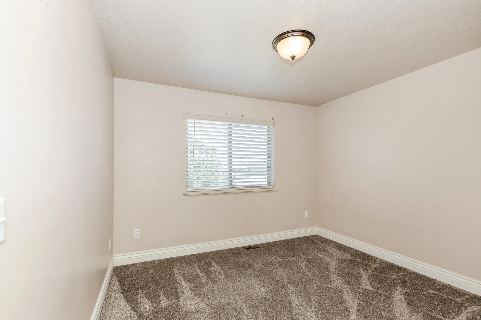 Room featuring neutral wall tones, textured carpet flooring, and white baseboards