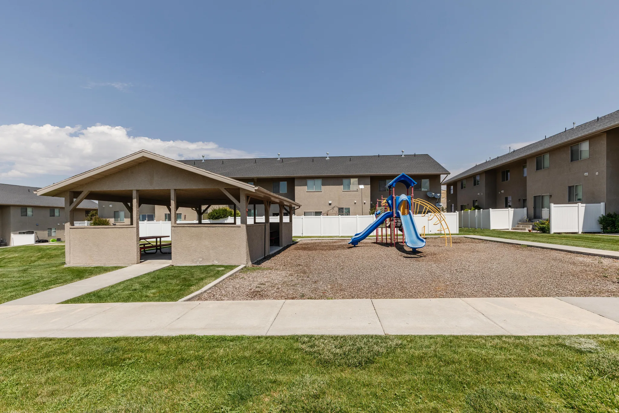 Outdoor amenities including a covered pavilion with built-in bench seating, a playground with slides and climbing features, and manicured green spaces