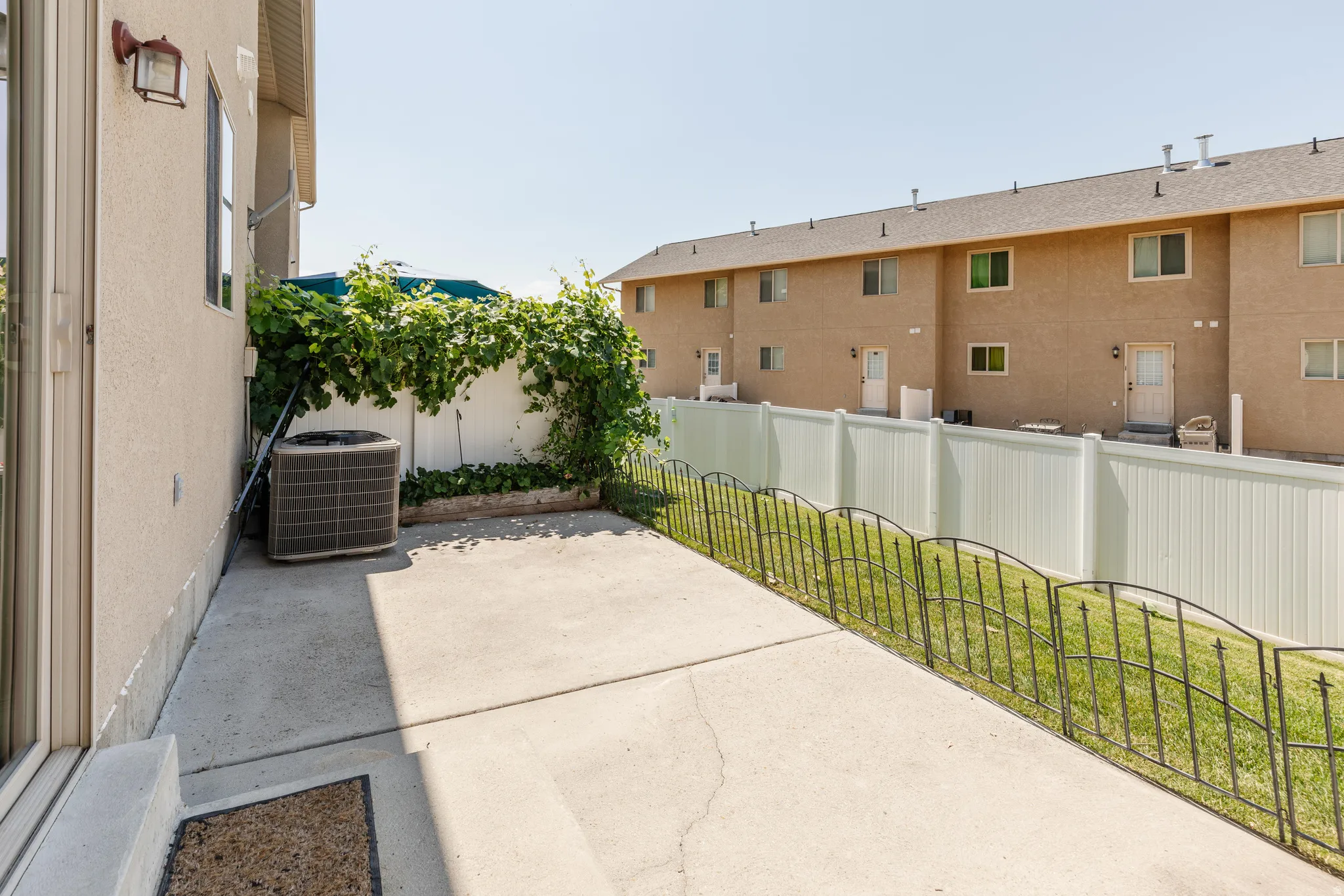 Concrete patio with an adjacent planted bed featuring established greenery and a conditioning unit