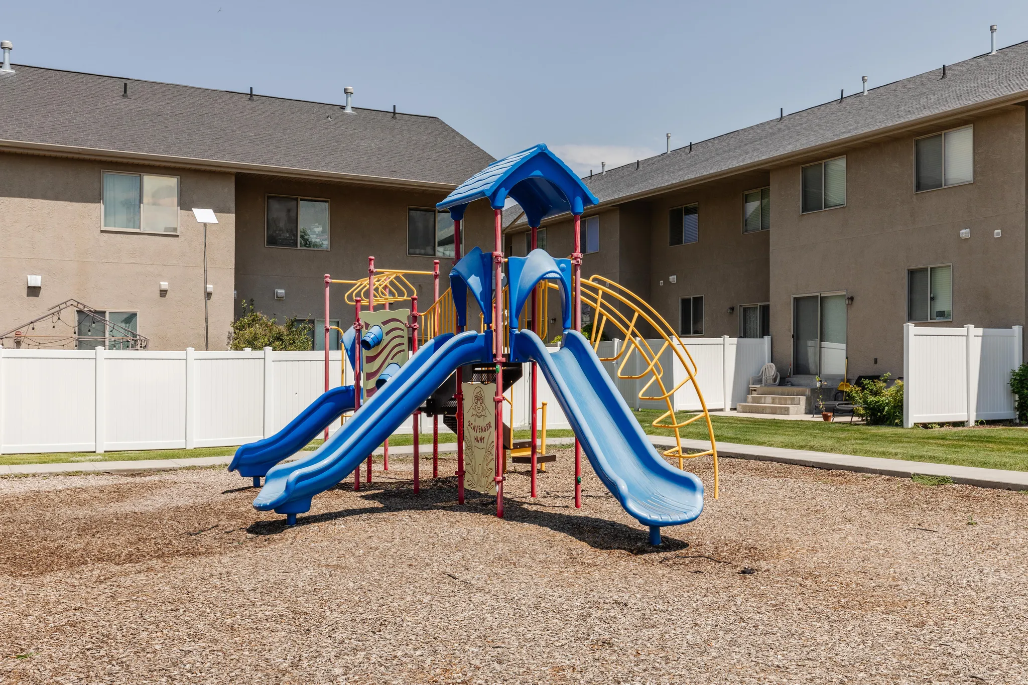 Community playground featuring a multi-level play structure with dual slides and climbing elements