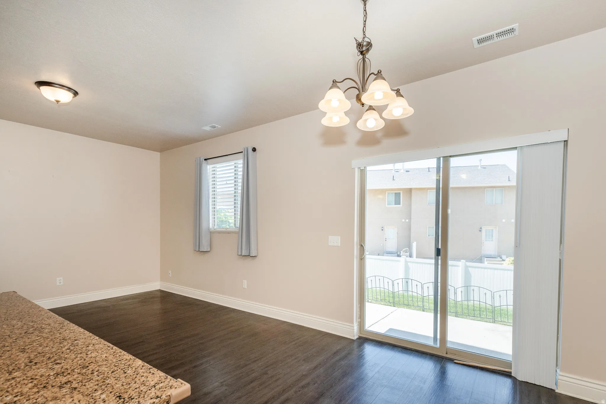 Spacious room featuring dark wood-finish flooring, light neutral wall tones, and white baseboards