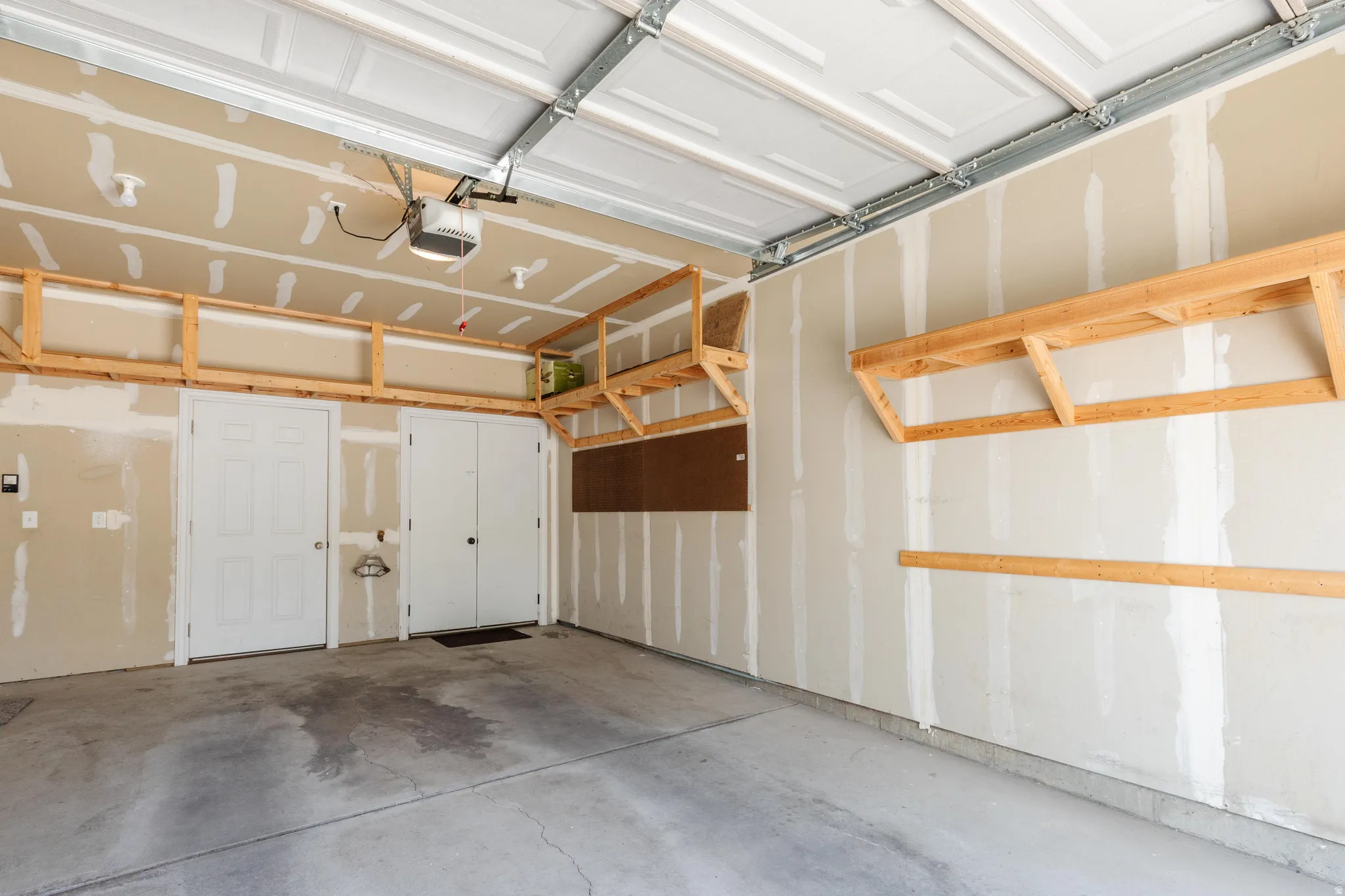 Attached garage featuring a concrete floor, built-in wooden shelving, and a garage door opener