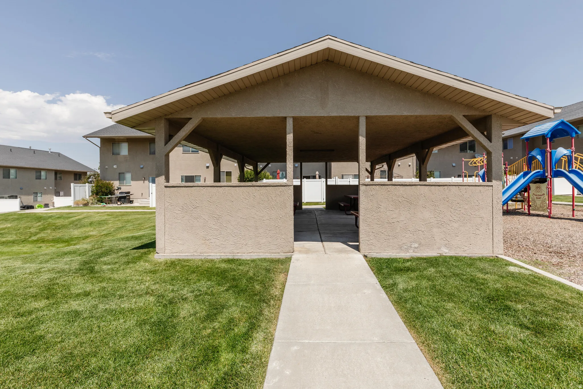 Expansive lawn surrounding a covered outdoor pavilion with a concrete walkway