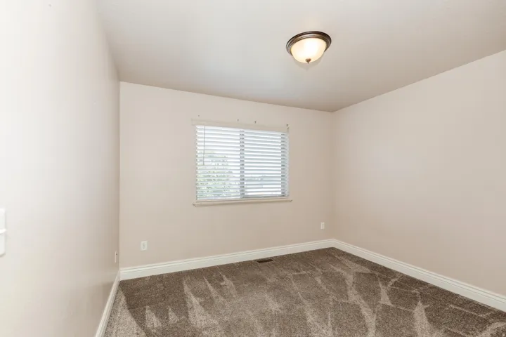 Room featuring neutral wall tones, textured carpet flooring, and white baseboards