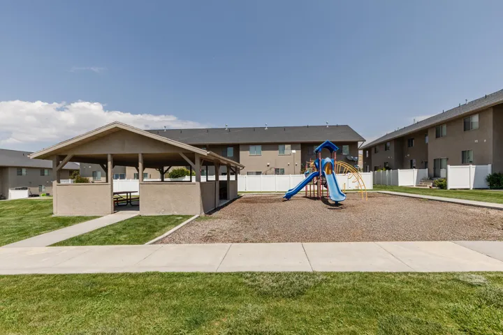 Outdoor amenities including a covered pavilion with built-in bench seating, a playground with slides and climbing features, and manicured green spaces