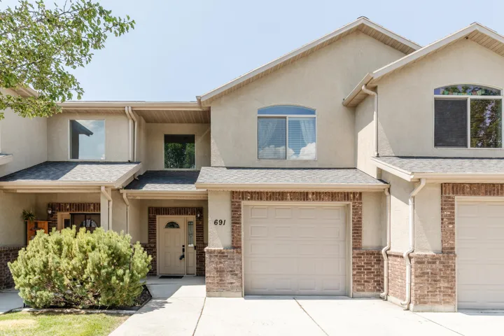 Stucco facade featuring brick accents and arched dormer windows