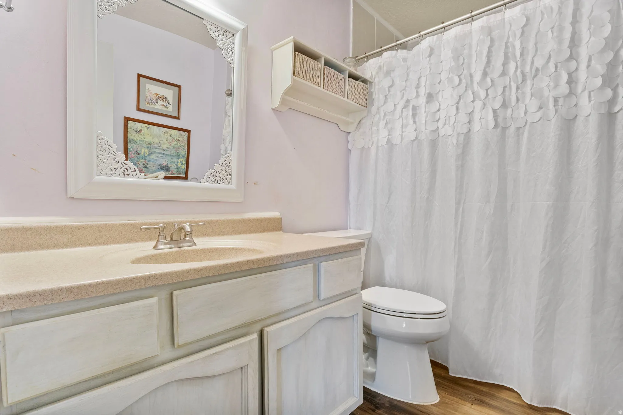 Bathroom featuring a single-sink vanity with a light-colored countertop, brushed nickel faucet, and a white framed mirror