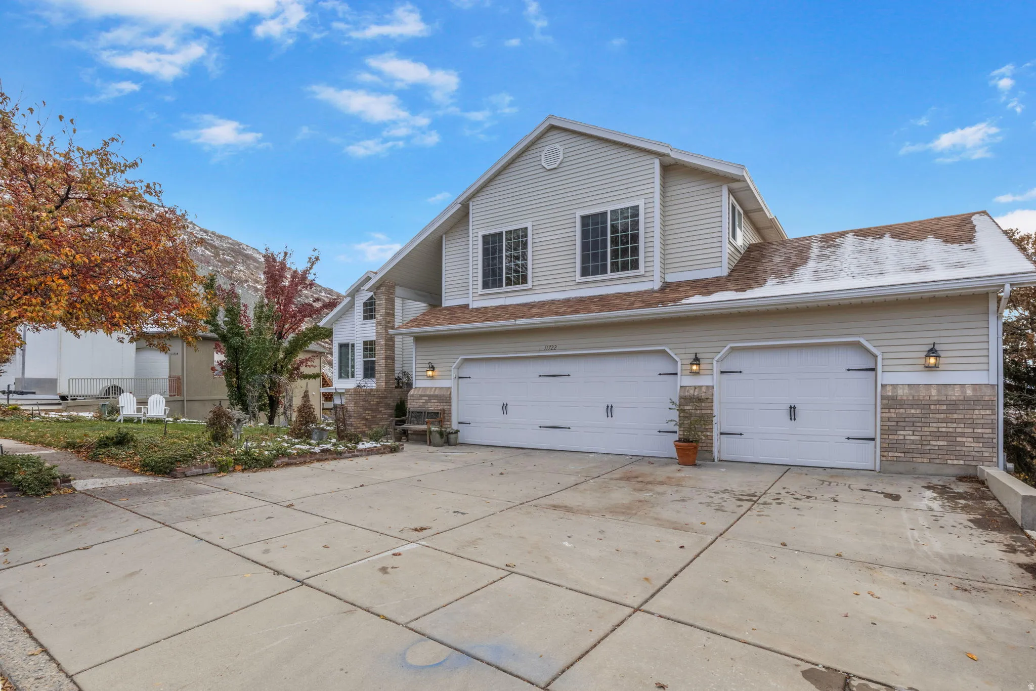 Two-story residence featuring light-colored siding and a multi-car driveway