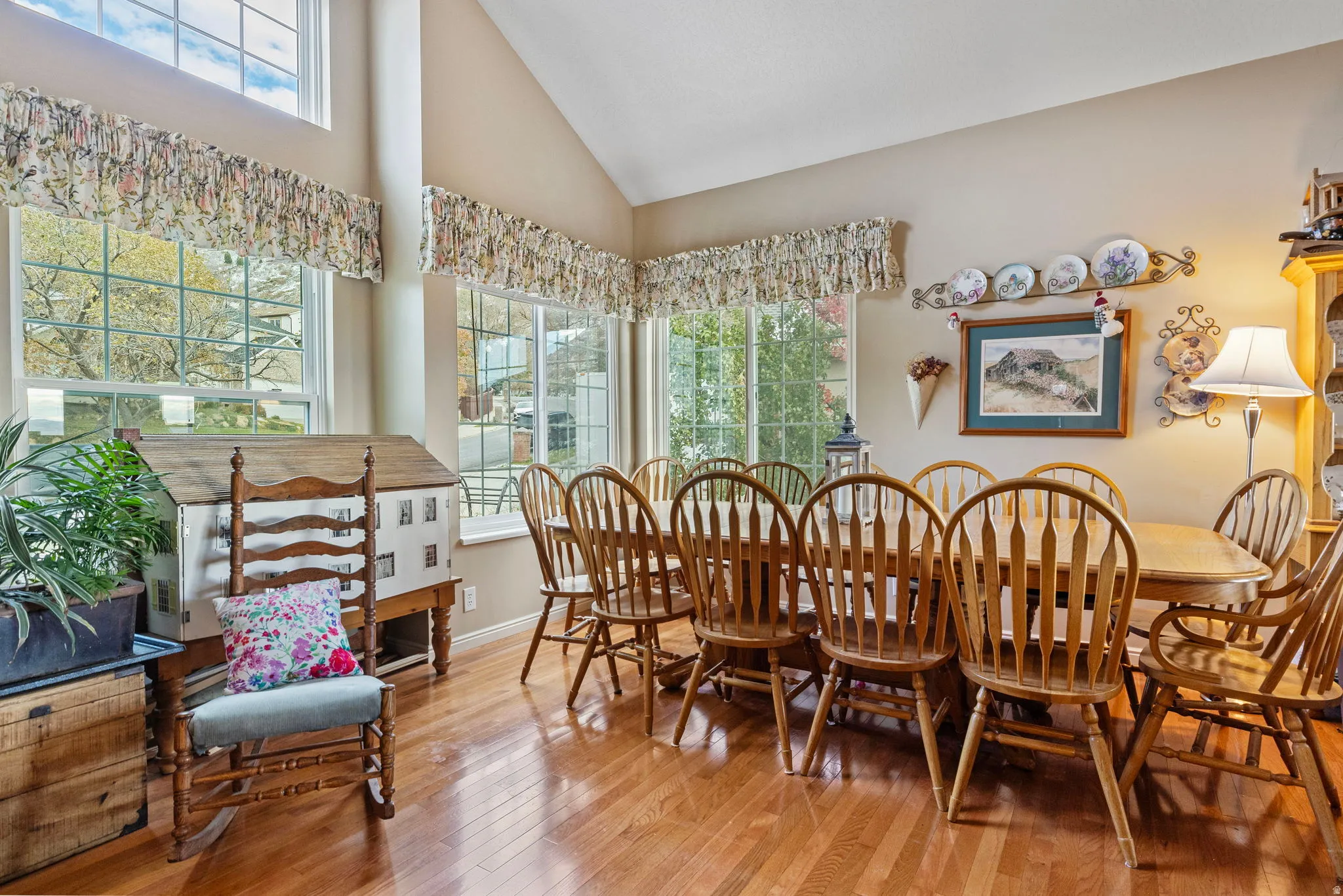 Spacious dining area featuring vaulted ceilings, ample natural light from multiple windows, and wood-finish flooring