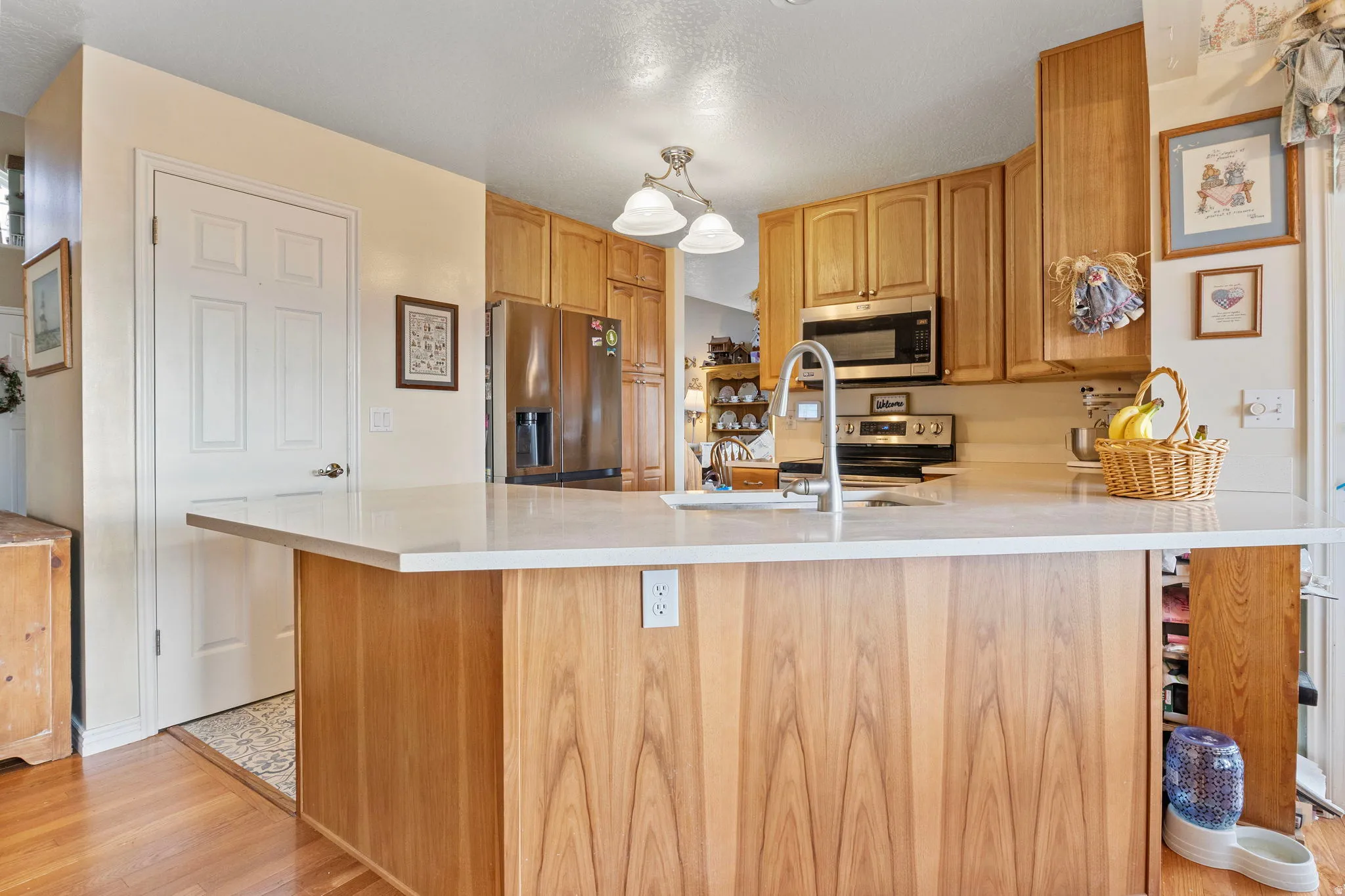 Kitchen island with a light-toned countertop, wood-finish base, and integrated sink with a gooseneck faucet