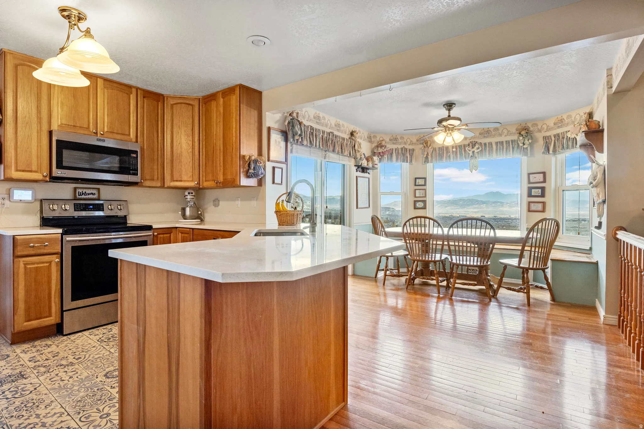Well-appointed kitchen featuring light wood cabinetry, stainless steel appliances, and a central island with a light-toned countertop