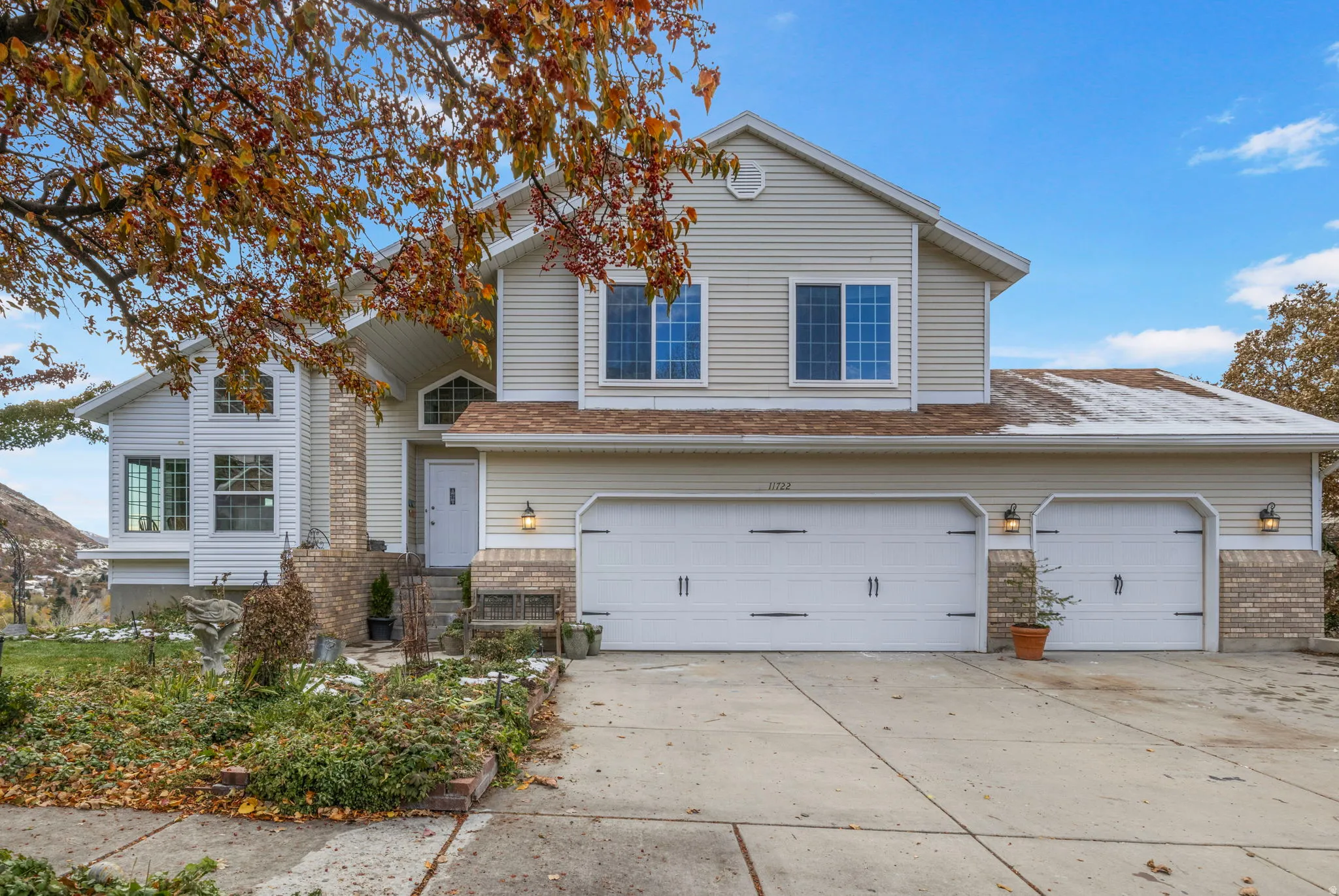 Multi-level residence featuring light-colored siding and a multi-car garage with individual doors