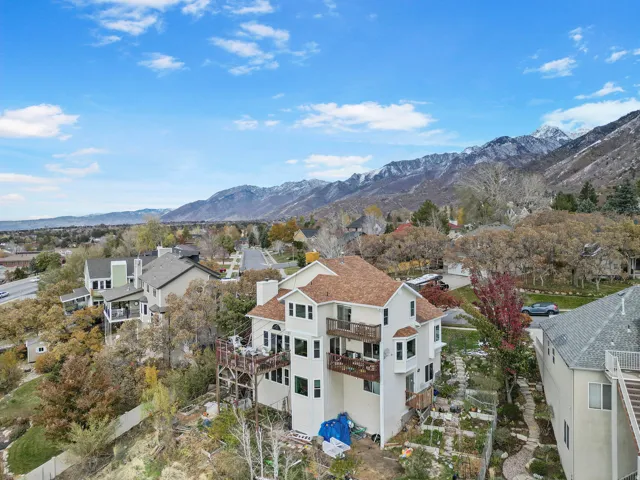 Multi-level residence featuring a light-colored exterior, brown shingle roofing, multiple balconies, and a terraced rear yard
