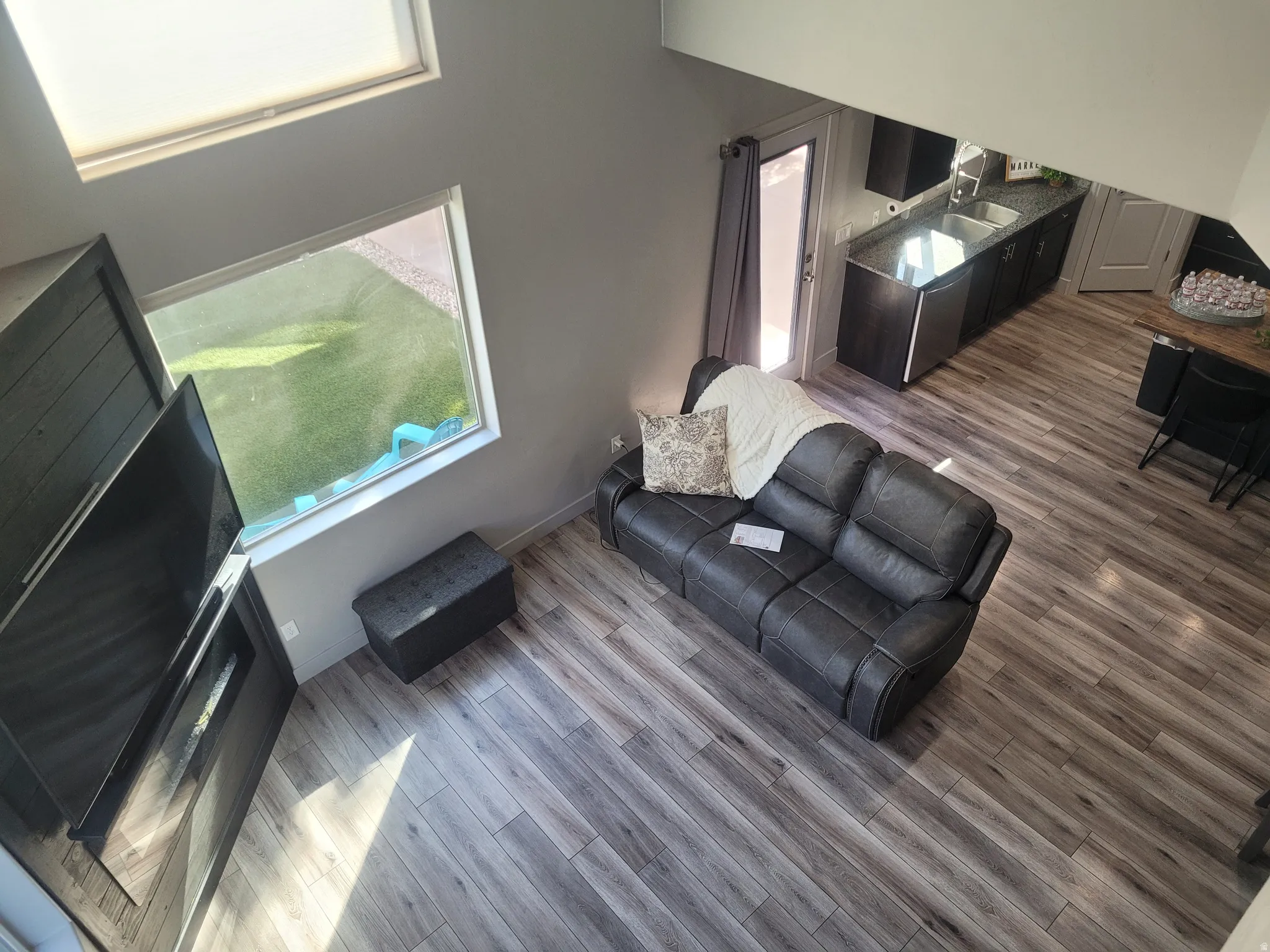 Open-concept living space featuring wood-finish flooring, a contemporary fireplace, and a large window
