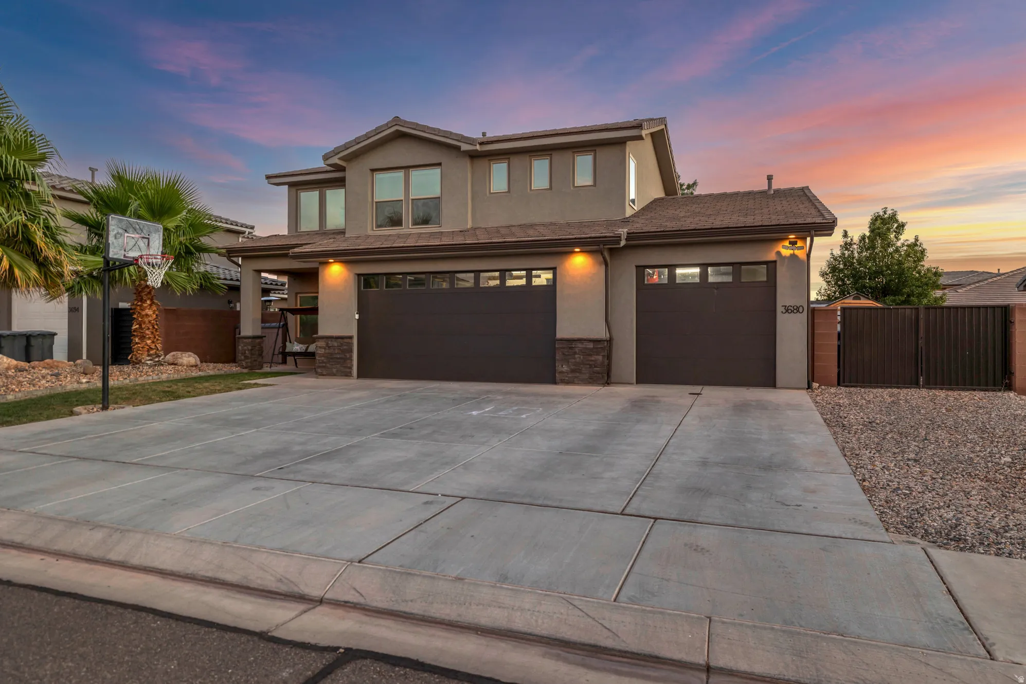 Contemporary stucco exterior featuring a two-car garage, an additional single-car garage, stone accents, and a concrete driveway