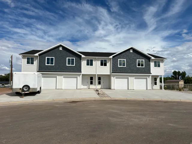 Modern townhome-style residences featuring two-tone exterior siding, white garage doors, and individual entryways