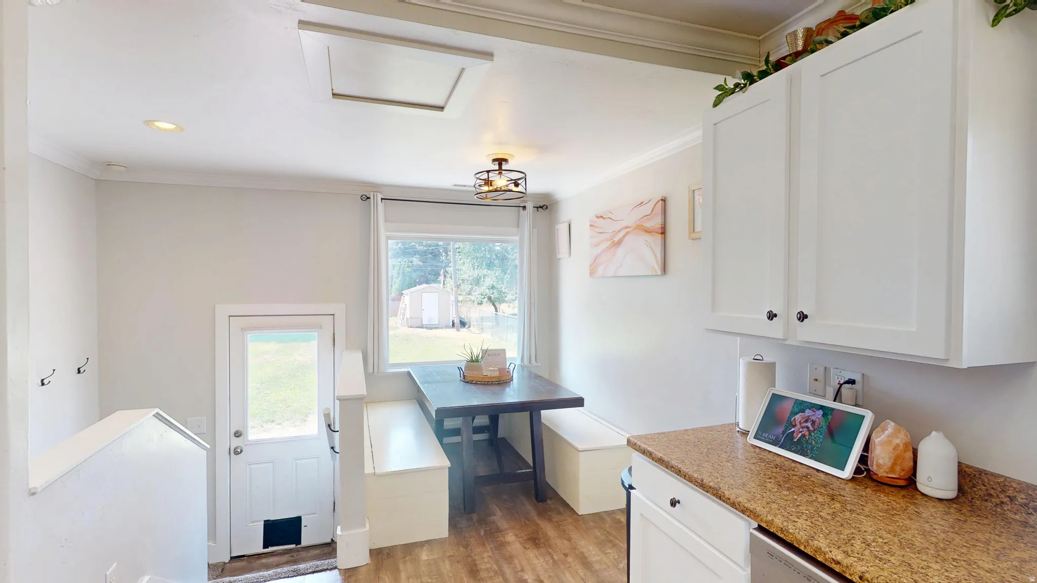 Kitchen and dining area featuring white cabinetry, wood-finish flooring, recessed lighting, and a window overlooking the property
