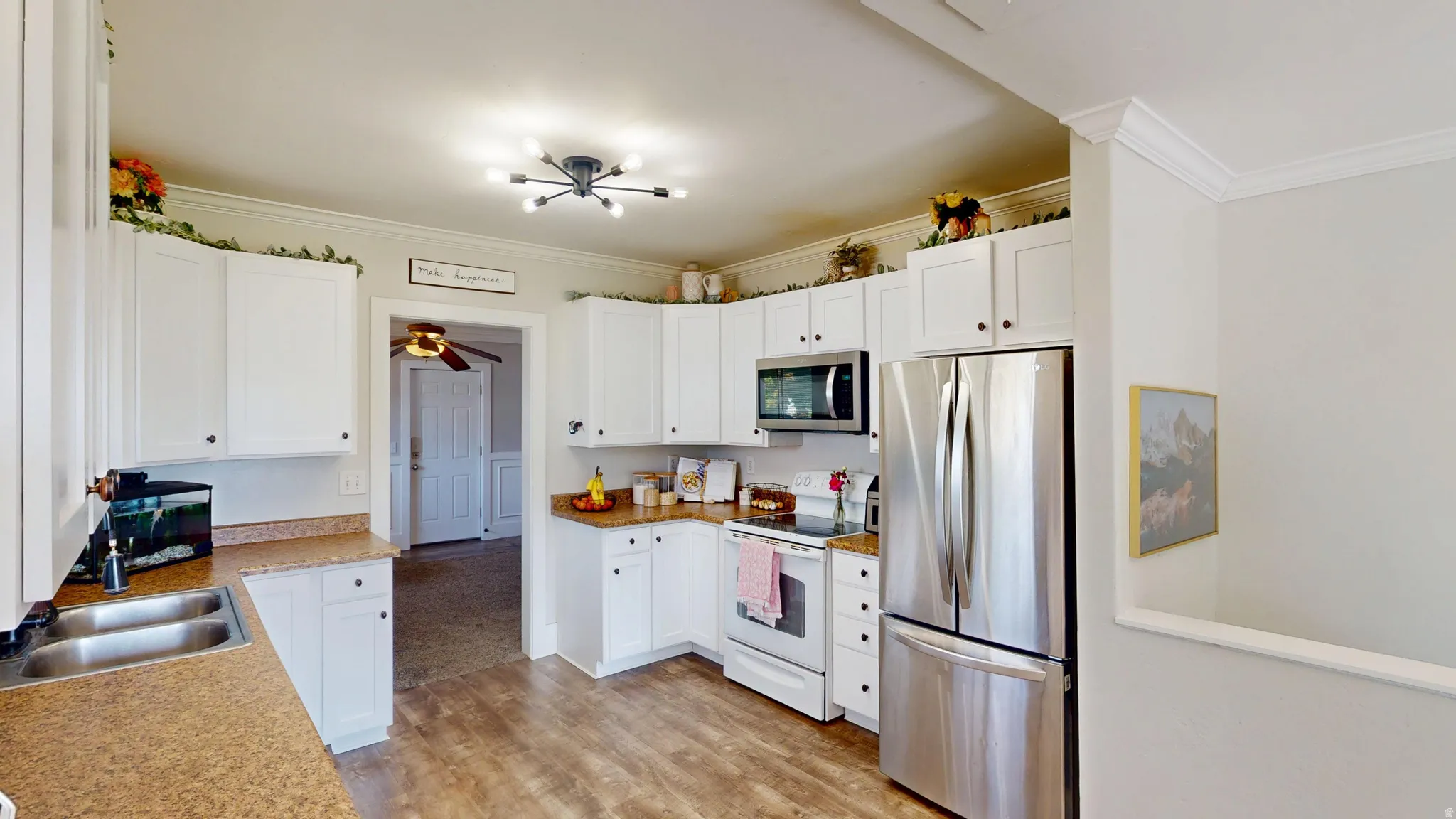 Kitchen featuring white cabinetry, light-toned countertops, a double basin stainless steel sink, and wood-finish flooring