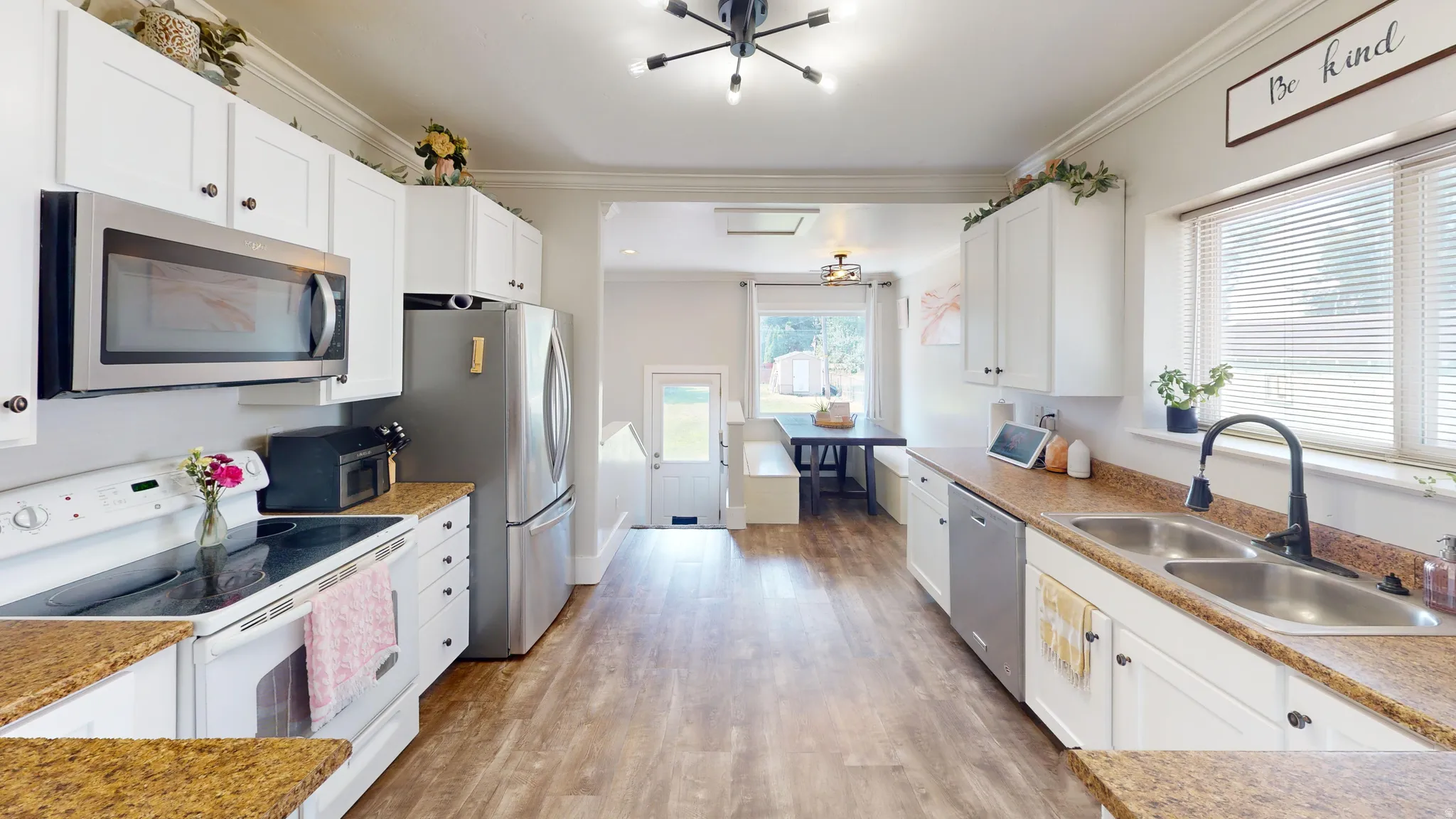 Kitchen featuring extensive white cabinetry, stainless steel appliances, wood-finish flooring, and a double basin sink with a matte black faucet