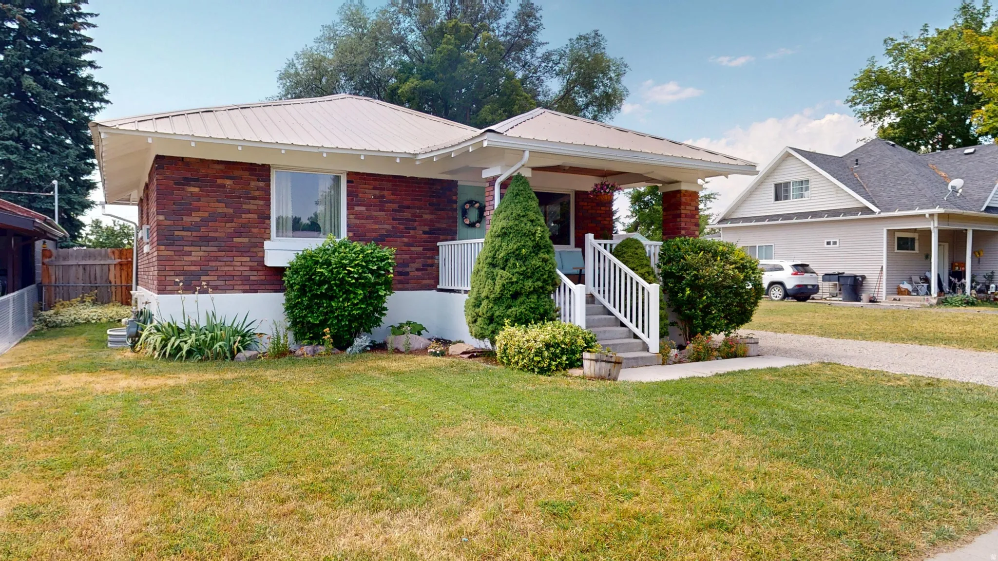 Brick exterior featuring a covered front porch with white railings and steps