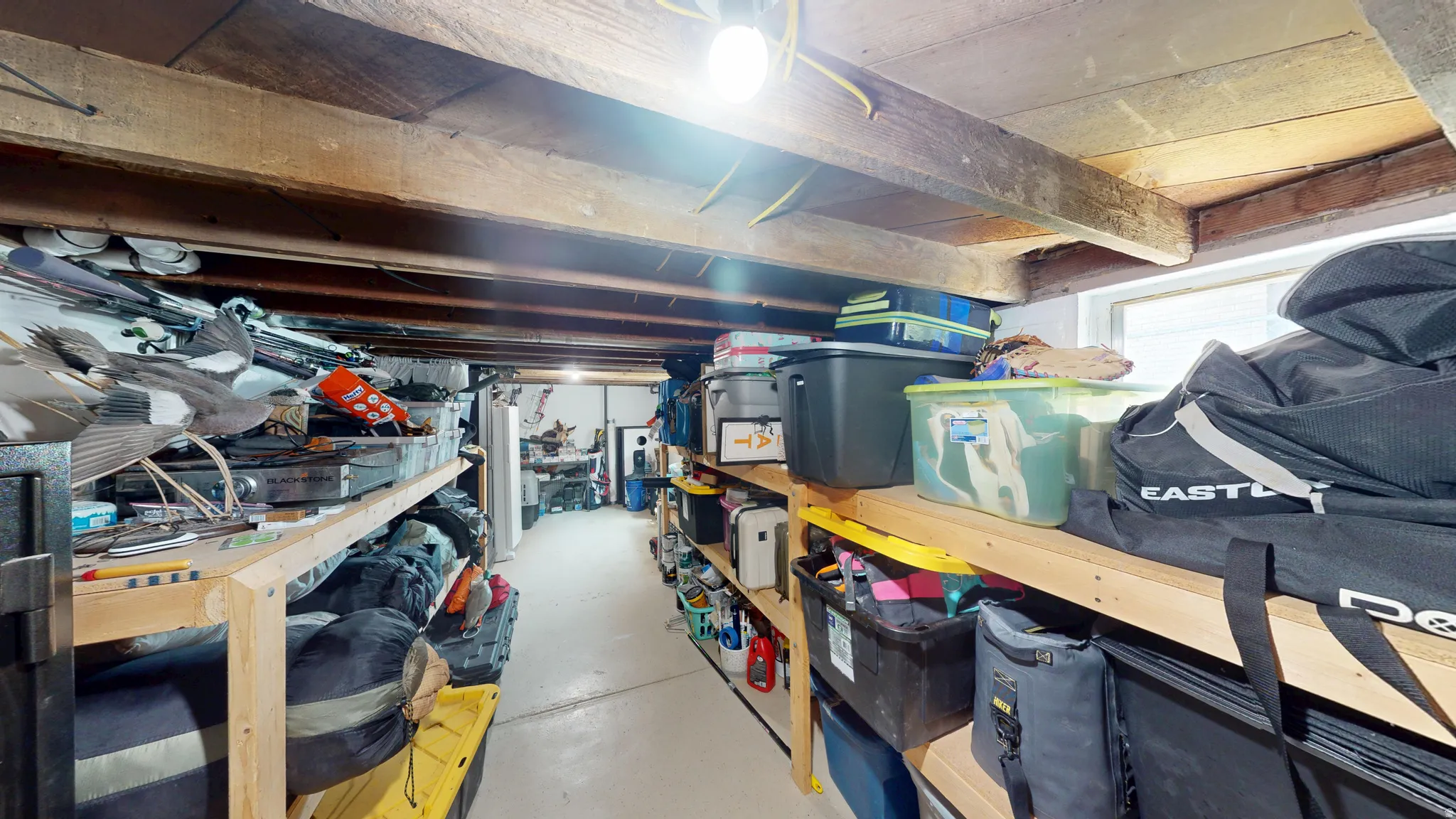 Unfinished basement space featuring exposed wooden ceiling beams and a concrete floor