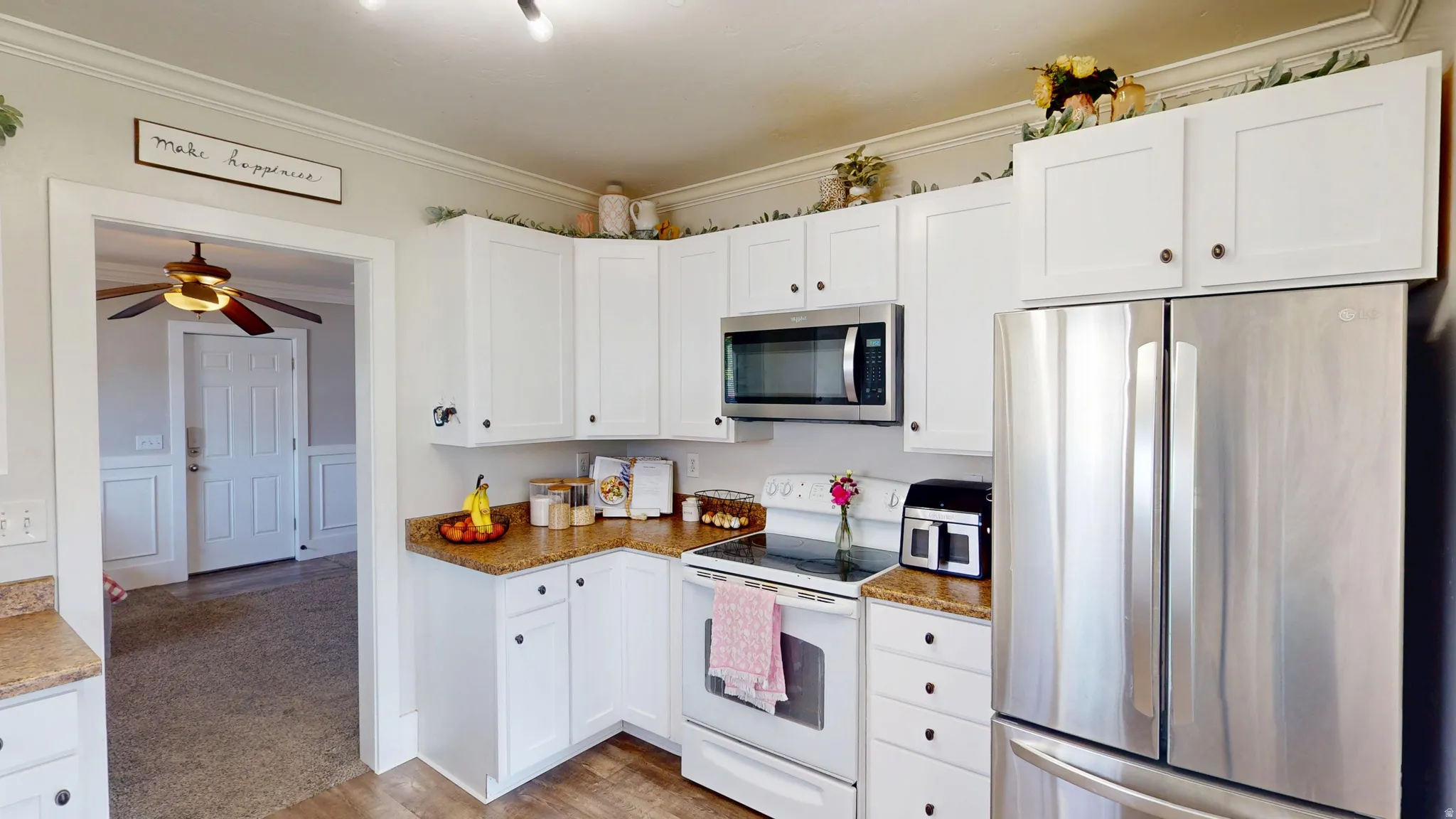 Modern kitchen featuring white cabinetry, wood-finish flooring, a stainless steel refrigerator, and built-in microwave