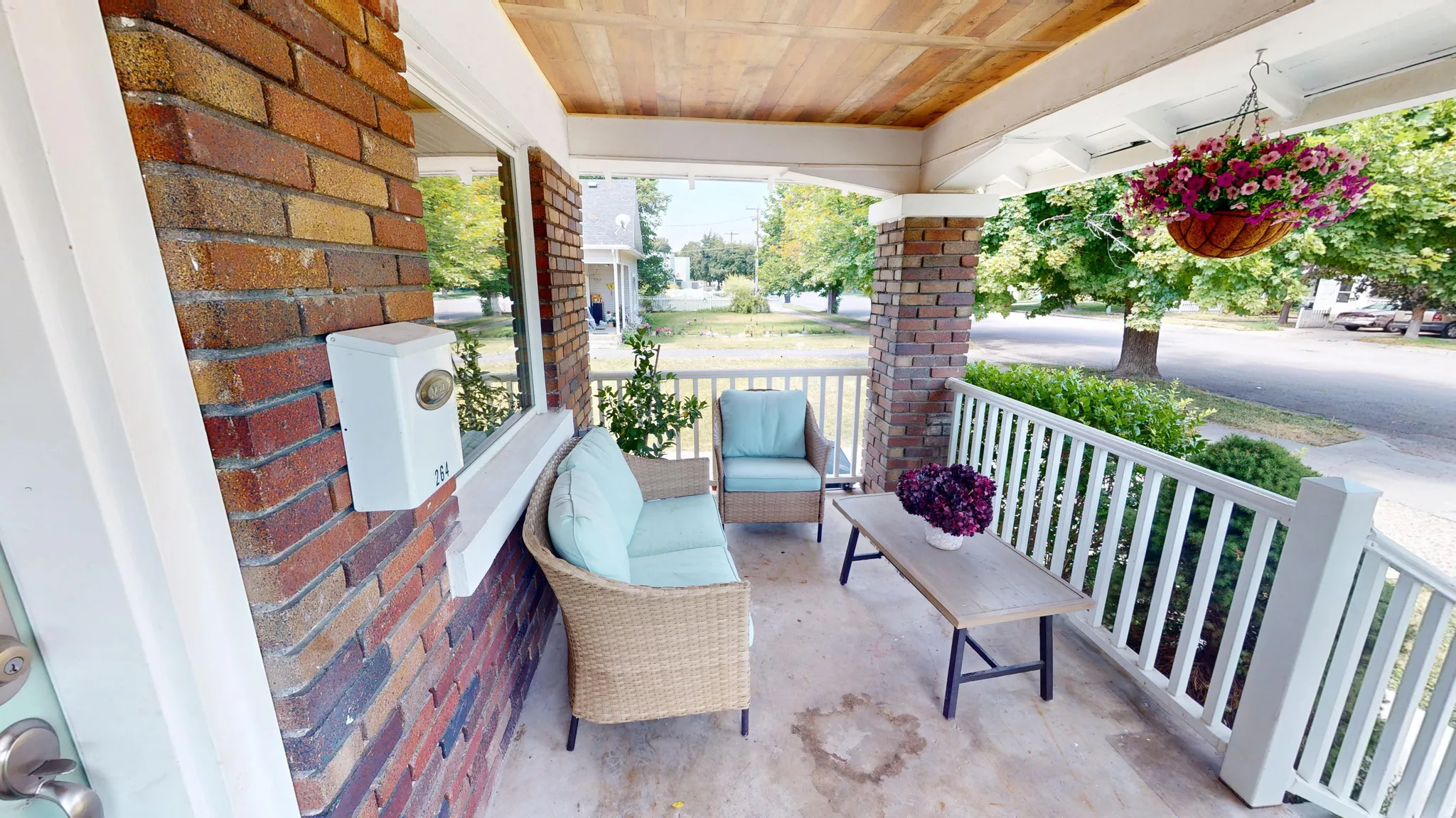 Inviting front porch featuring brick siding, white railings, a wood-paneled ceiling, and a prominent window