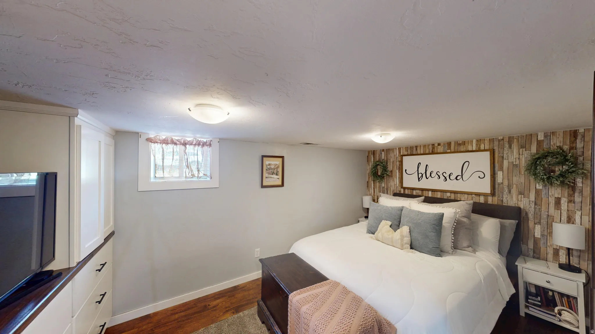 Room featuring a distressed wood-paneled accent wall, a built-in cabinetry unit, wood-finish flooring, and a flush-mount ceiling light fixture