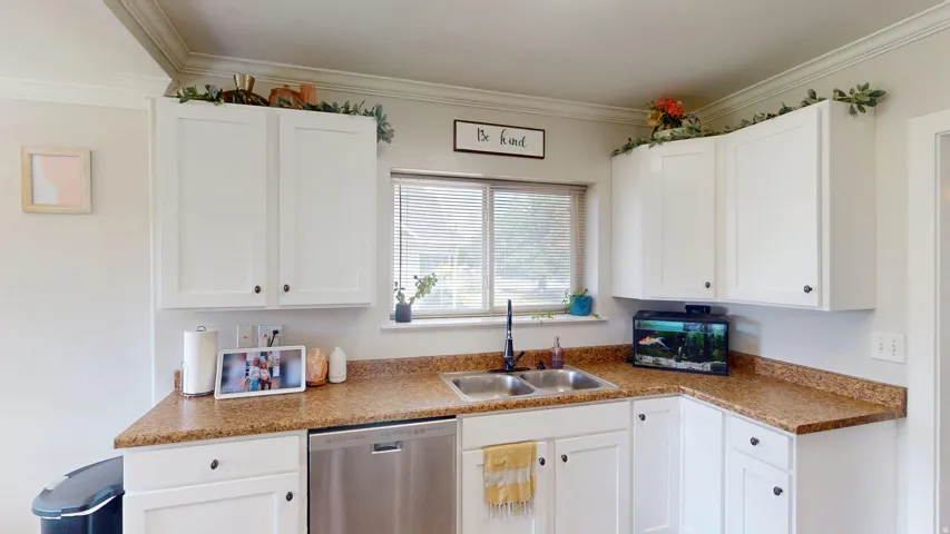 Kitchen featuring white cabinetry with dark hardware, a stainless steel dishwasher, a double basin sink with a matte black faucet, and a window with horizontal blinds