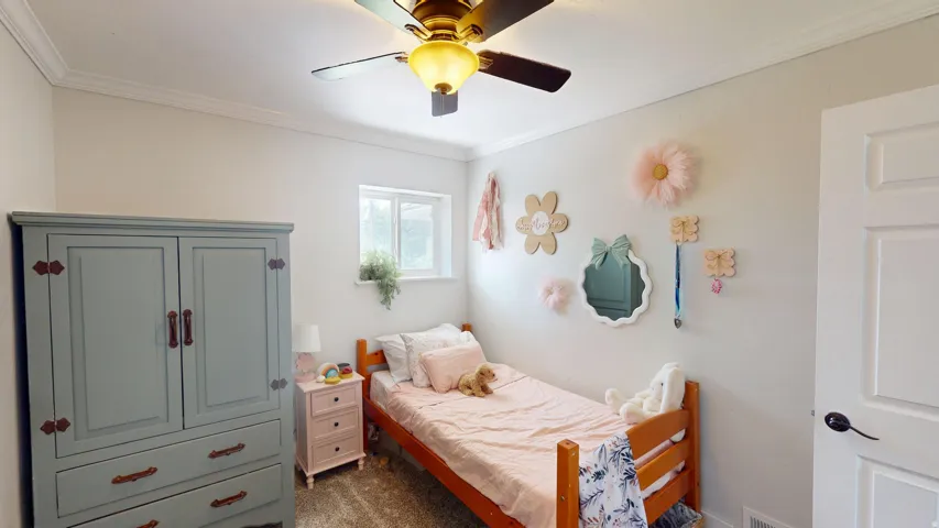 Bright room featuring a window with natural light, crown molding, a ceiling fan with integrated lighting, and light-toned walls