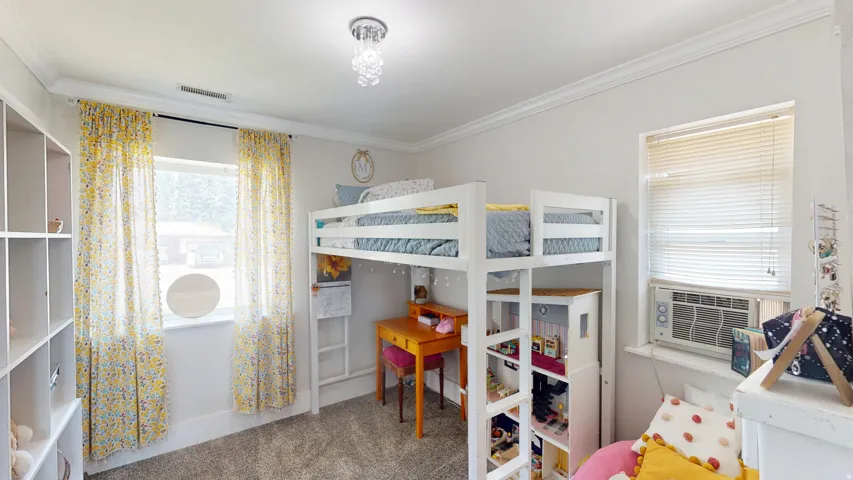 Bedroom featuring neutral wall paint, gray carpeting, a built-in shelving unit, a window with blinds, and crown molding
