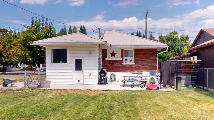 Rear exterior featuring a metal roof, brick and siding finishes, and a concrete patio