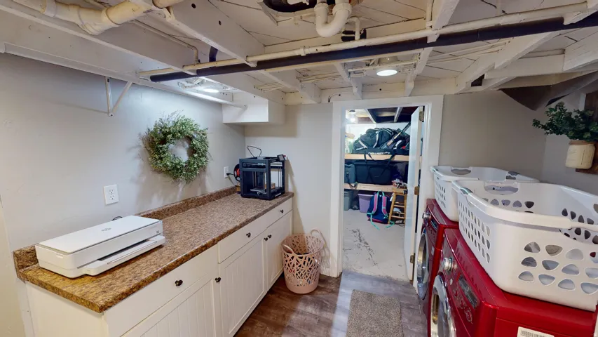 Functional utility space featuring wood-finish flooring, white cabinetry with dark hardware, and a speckled countertop