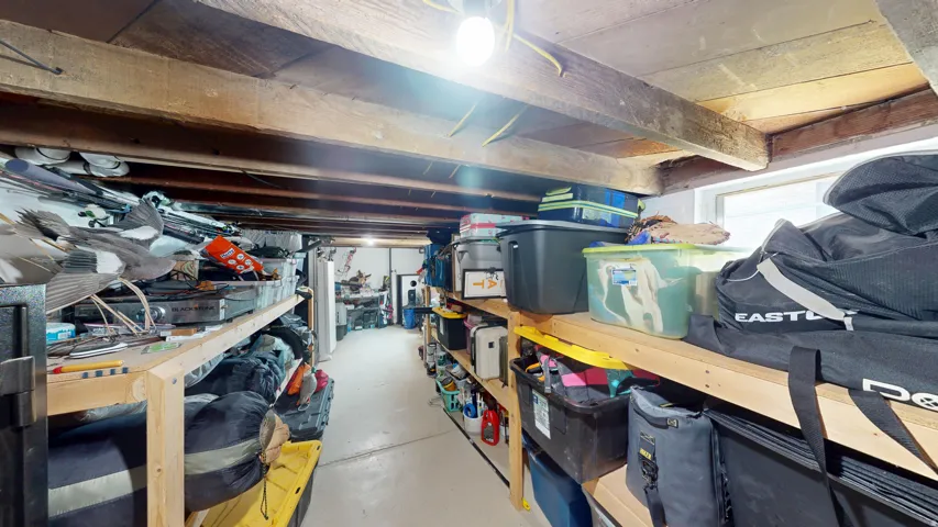 Unfinished basement space featuring exposed wooden ceiling beams and a concrete floor