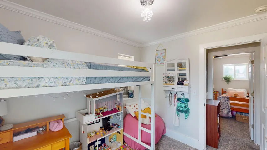 White bunk bed structure with a lower bed, white walls, and crown molding