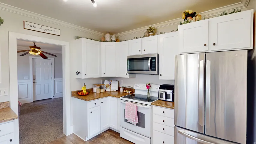 Modern kitchen featuring white cabinetry, wood-finish flooring, a stainless steel refrigerator, and built-in microwave