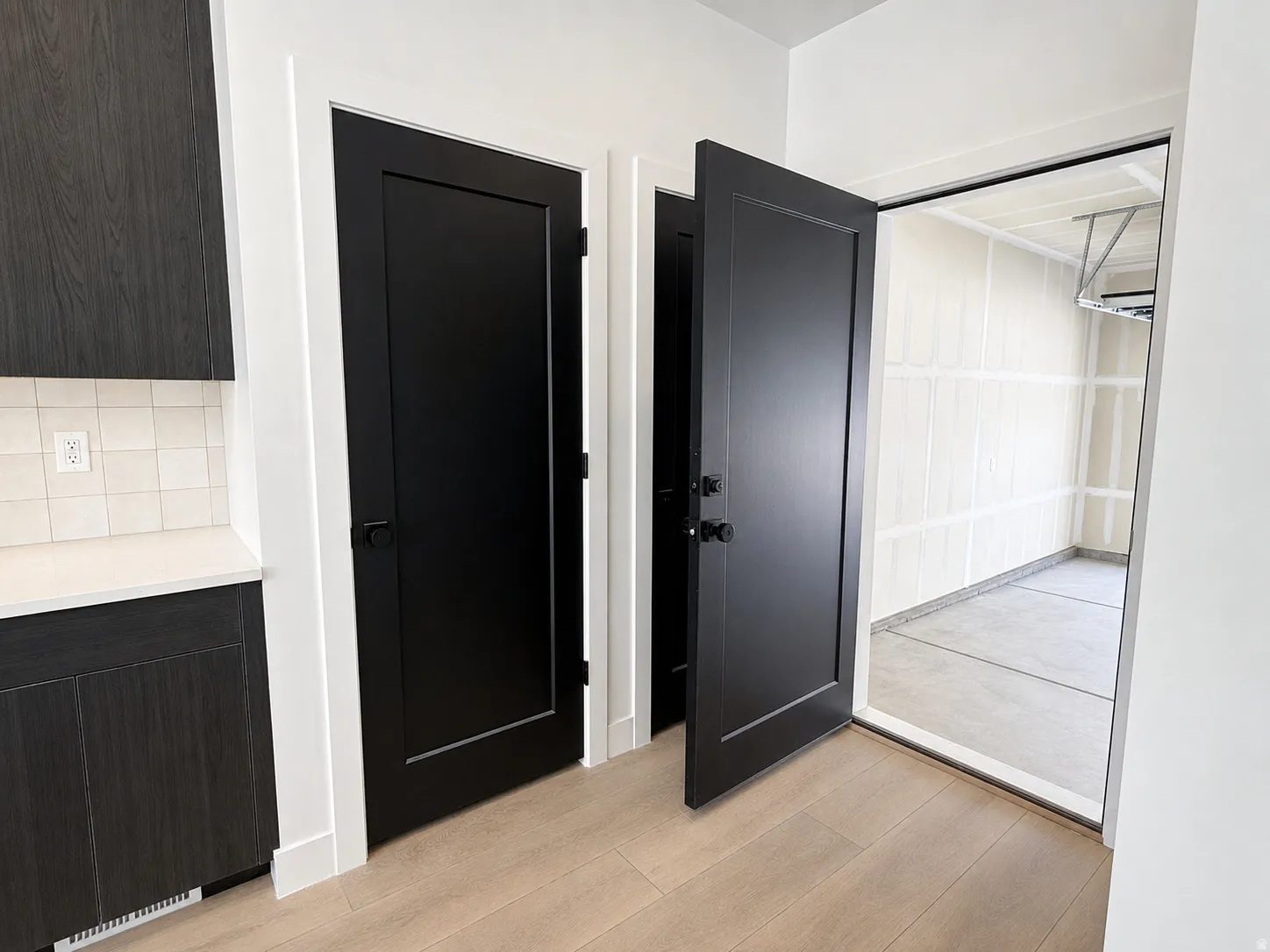 Entryway with wood-finish flooring, two panel-style doors, and dark wood-grain cabinetry