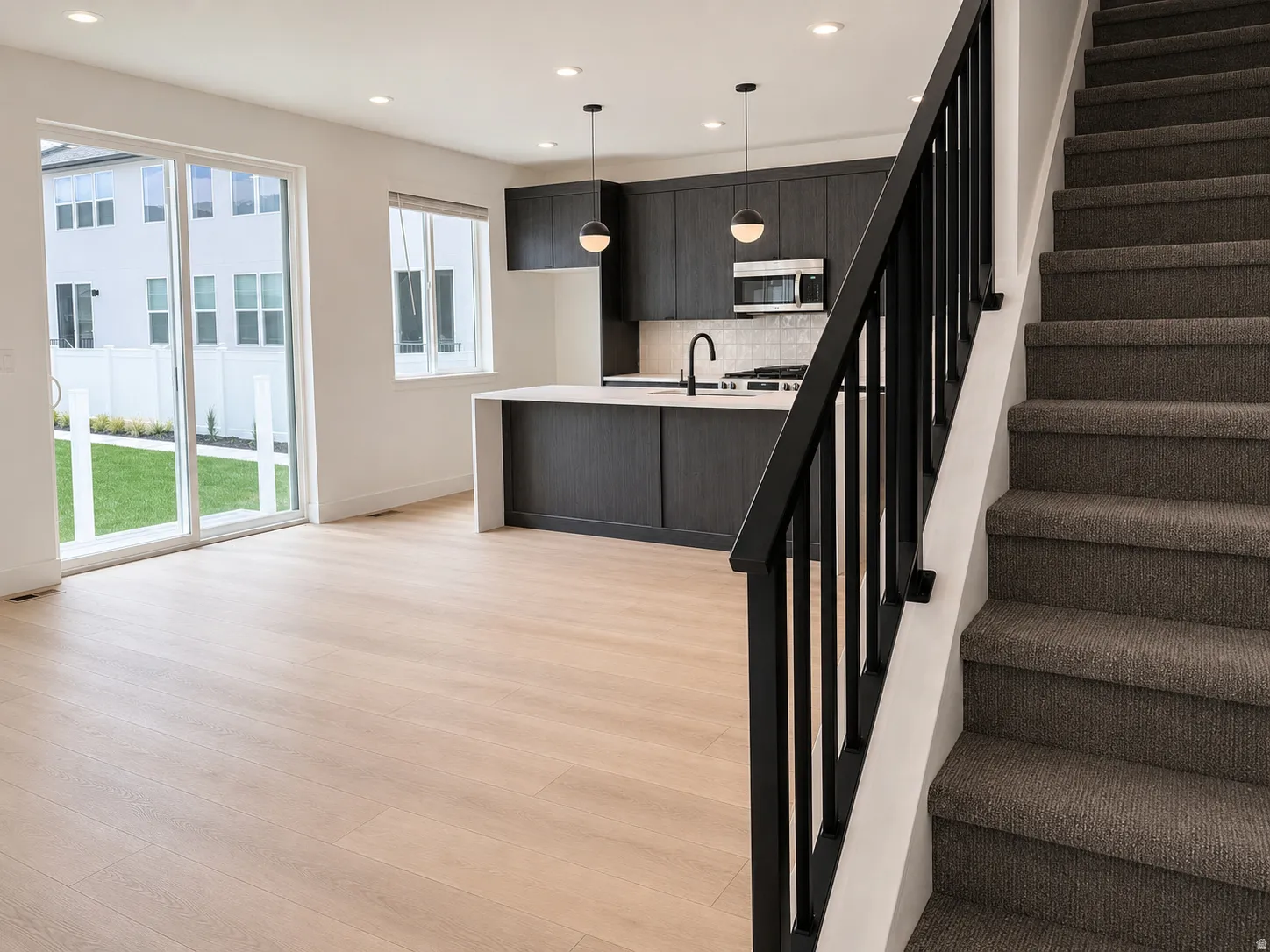 Open-concept living area with wood-finish flooring, recessed lighting, and a modern kitchen