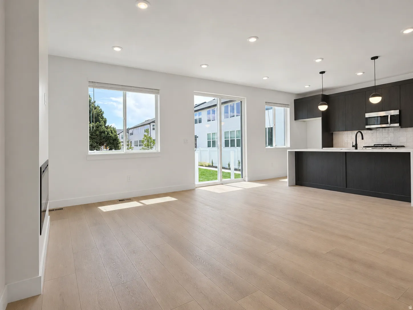 Open-concept living space featuring wood-finish flooring, recessed lighting, and a linear electric fireplace