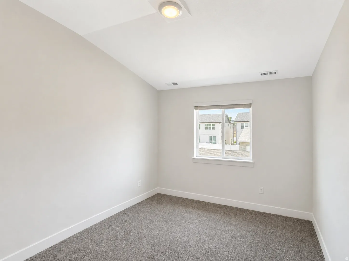 Neutral tone walls featuring a single window with a white frame and blinds